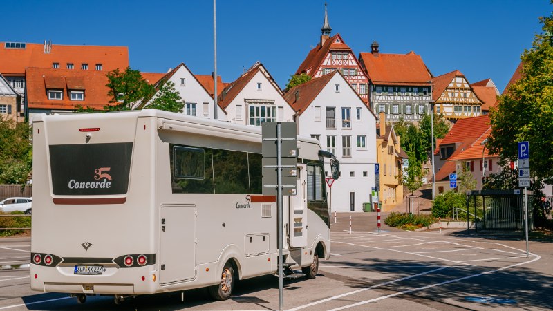 Wohnmobil auf einem Parkplatz in Bietigheim-Bissingen, umgeben von historischen Fachwerkhäusern und blauem Himmel., © SMG, Thomas Niedermüller