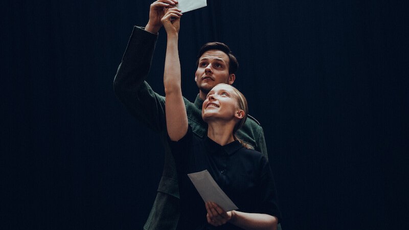 Zwei Personen halten Umschl&auml;ge in die Luft, als ob sie etwas pr&auml;sentieren. Der Hintergrund ist dunkel, was den Fokus auf die Personen lenkt., &copy; Festspielhaus Neuschwanstein gGmbh