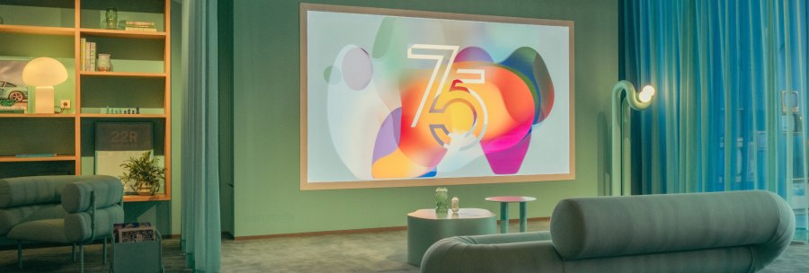 Modern room with sofa, shelf and large screen showing the number 75. Stylish lighting and decoration., © Porsche AG