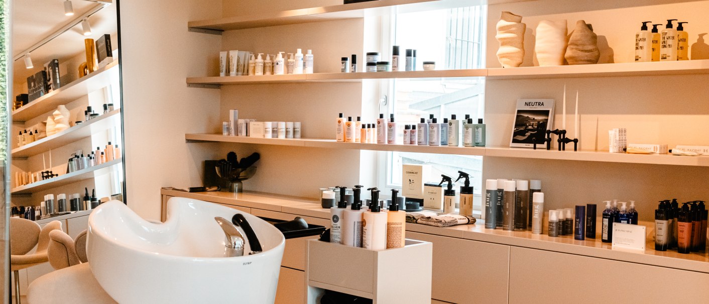 Moderner Friseursalon mit Waschbecken, Regalen voller Haarpflegeprodukte und stilvoller Einrichtung., © SMG_Sarah Schmid