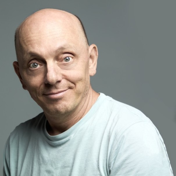 Ein Mann mit Glatze und hellem T-Shirt l&auml;chelt in die Kamera. Der Hintergrund ist grau., &copy; Renitenztheater Stuttgart e.V.