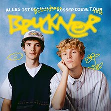 Zwei junge M&auml;nner posieren vor einem blauen Hintergrund. Der Schriftzug 'Bruckner - Alles ist beschissen au&szlig;er diese Tour 2026' ist dar&uuml;ber zu sehen., &copy; links im Bild