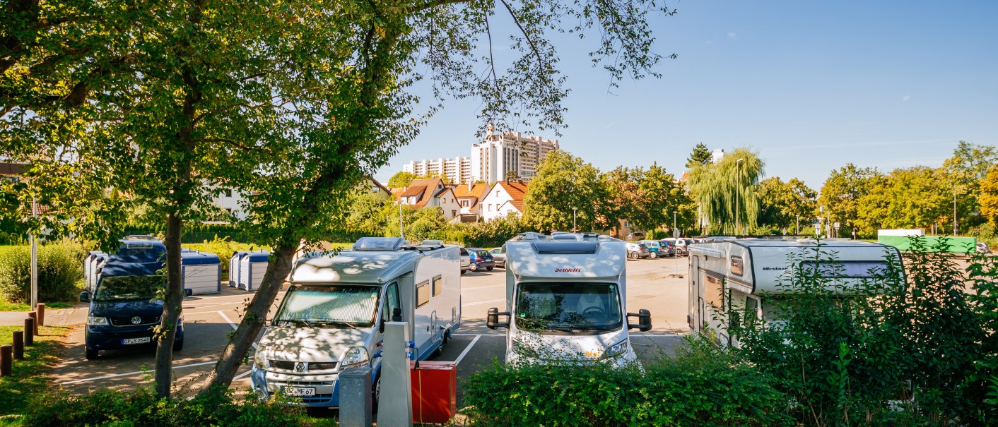 Wohnmobilstellplatz in Leonberg mit geparkten Wohnmobilen, umgeben von Bäumen und Gebäuden im Hintergrund bei klarem Himmel., © Stuttgart-Marketing GmbH, Thomas Niedermüller
