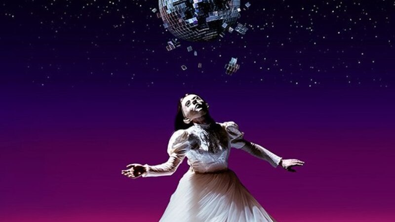 A woman in a white dress dances under a broken disco ball. The background is a starry sky, the floor is covered with garbage bags., &copy; Theaterhaus Stuttgart e.V.