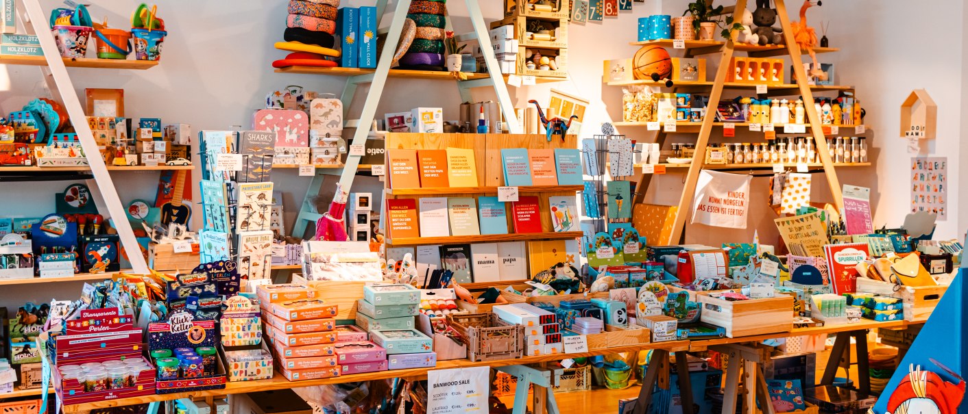 Ein bunter Spielzeugladen mit Regalen voller Bücher, Spiele und Spielzeug. Eine Pippi Langstrumpf-Figur ist im Vordergrund zu sehen., © SMG_Sarah Schmid