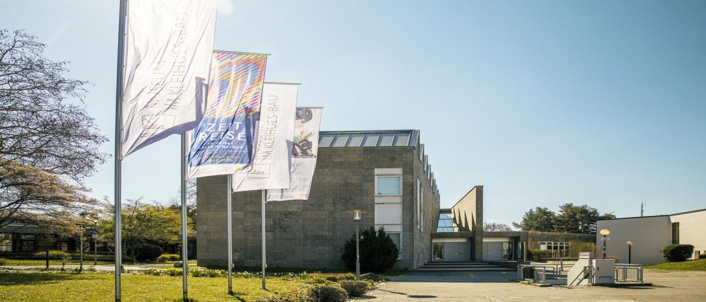 Das Museum Im Kleinhues-Bau in Kornwestheim, moderne Architektur mit mehreren Fahnen im Vordergrund, sonniger Tag., &copy; SMG, Sarah Schmid