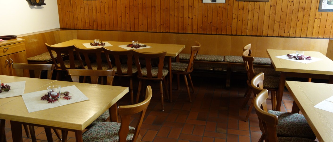 A cozy dining room with wooden tables and chairs, decorated with pictures on a wood-paneled wall., &copy; Besenwirtschaft Familie Nerz