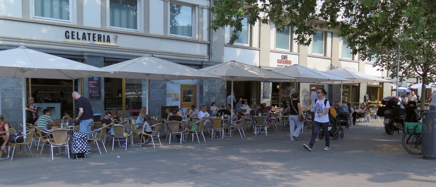 Menschen sitzen unter Sonnenschirmen vor der Gelateria Kaiserbau am Marienplatz. Einige Passanten gehen vorbei., &copy; Stuttgart-Marketing GmbH