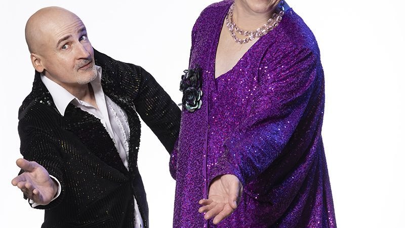 Ein humorvolles Duo posiert in auffälliger Kleidung. Der Mann trägt einen schwarzen Anzug, die andere Person ein lila Glitzerkleid., © Renitenztheater Stuttgart e.V. Ein humorvolles Duo posiert in auffälliger Kleidung. Der Mann trägt einen schwarzen Anzug, die andere Person ein lila Glitzerkleid., © Renitenztheater Stuttgart e.V.