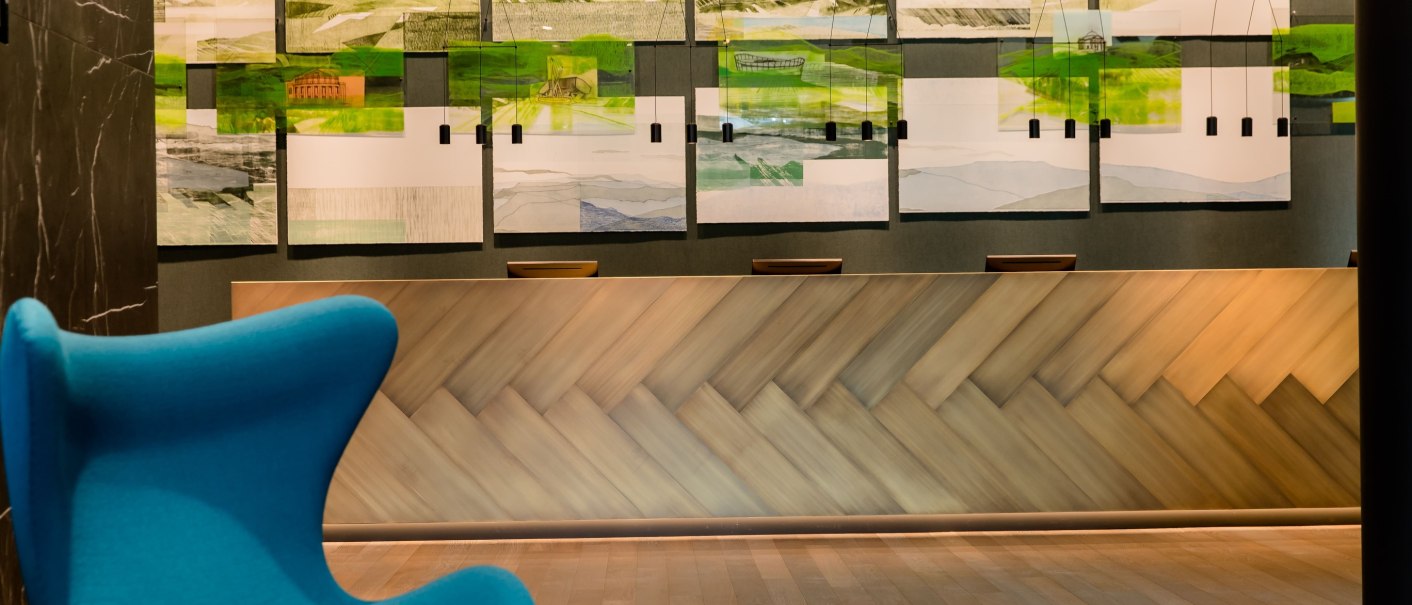 Modern reception with wooden counter, blue seating and landscape pictures on the wall. Elegant, inviting ambience., &copy; Motel One - Stuttgart Hauptbahnhof