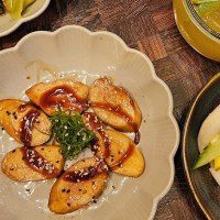 A plate of vegan dumplings in sauce, a bao bun with vegetables and a drink with ice cubes on a wooden table., &copy; SMG