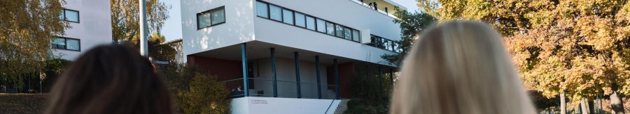 Two people look at the Le Corbusier house in the Weißenhofsiedlung. Modern building with clear lines, surrounded by autumnal trees., © Stuttgart-Marketing GmbH, wpsteinheisser