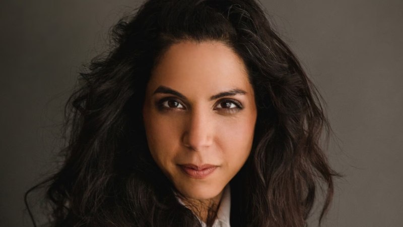 Portr&auml;t einer Frau mit dunklem, lockigem Haar und ernstem Blick vor einem grauen Hintergrund., &copy; Stefanie J&auml;ger