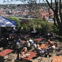 Ein Biergarten auf der Karlsh&ouml;he mit Blick auf Stuttgart. Menschen sitzen an Tischen unter Sonnenschirmen, umgeben von B&auml;umen und einer Stadtansicht., &copy; Stuttgart-Marketing GmbH