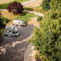 Two mobile homes are parked on a pitch surrounded by trees. A tennis court can be seen on the right of the picture., © Blu Dolci Artwork Two mobile homes are parked on a pitch surrounded by trees. A tennis court can be seen on the right of the picture., © Blu Dolci Artwork