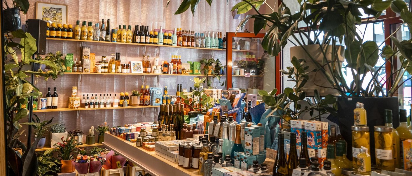 A store with shelves full of colorful bottles, cans and plants. The atmosphere is lively and inviting., © SMG, Sarah Schmid
