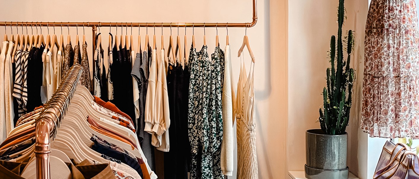 Fashion store with clothes rail full of clothes, cactus in the corner and mannequin in the window. Elegant lighting from above., © MAGASIN Geißstrasse 15, Stuttgart