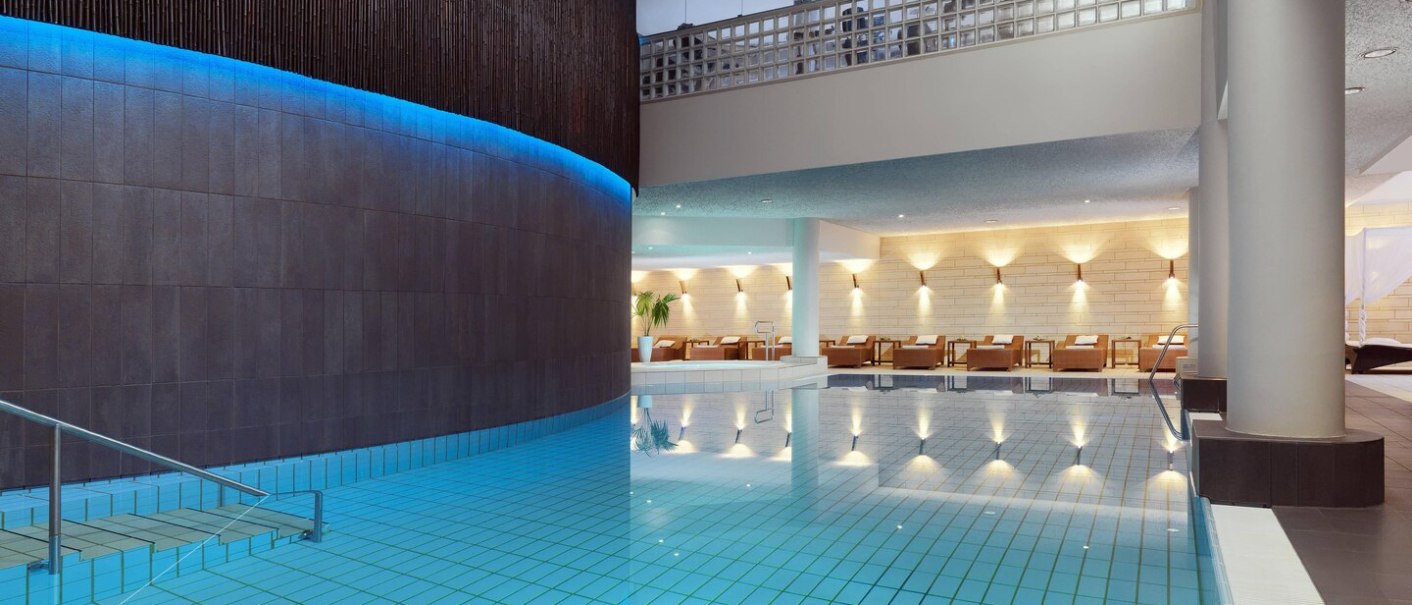 Moderner Hotelpool mit blauer Beleuchtung, Liegestühle im Hintergrund, stilvolle Architektur., © Hotel Le Méridien Moderner Hotelpool mit blauer Beleuchtung, Liegestühle im Hintergrund, stilvolle Architektur., © Hotel Le Méridien