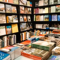 Bücherregale in einer Buchhandlung mit einer Vielzahl von Büchern zu Architektur und Kunst. Stapel von Büchern auf einem Tisch in der Mitte., © Walther König Bücherregale in einer Buchhandlung mit einer Vielzahl von Büchern zu Architektur und Kunst. Stapel von Büchern auf einem Tisch in der Mitte., © Walther König