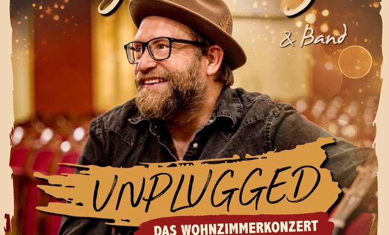 Gregor Meyle auf einem Albumcover mit Hut und Brille, l&auml;chelnd in einem Konzertsaal. Text: 'Unplugged - Das Wohnzimmerkonzert'., &copy; C2 Concerts GmbH