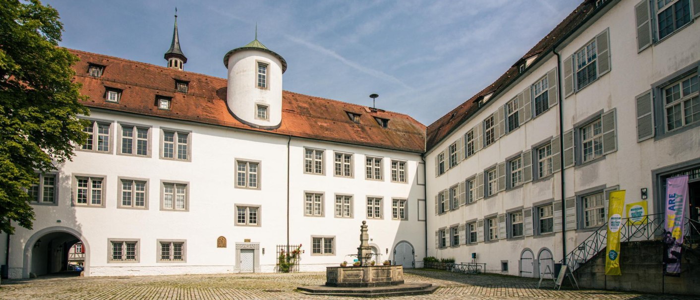 The courtyard of Waldenbuch Castle features white buildings with red roofs and a central fountain. A blue sky completes the scene., &copy; SMG Stuttgart Marketing GmbH - Sarah Schmid