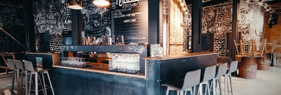 Modern bar with industrial design, high stools and stylish lamps. Walls with graffiti and a blackboard with drink names., © Kraftpaule GmbH Modern bar with industrial design, high stools and stylish lamps. Walls with graffiti and a blackboard with drink names., © Kraftpaule GmbH