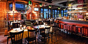 Gem&uuml;tliche Brauerei mit Kupferkesseln, Holztischen und -st&uuml;hlen. Barbereich mit roten Hockern, warmes Ambiente durch Beleuchtung und Dekor., &copy; Parkhotel Stuttgart Messe-Airport