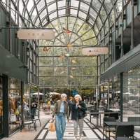 Zwei Personen schlendern durch die Calwer Passage mit Geschäften und Cafés unter einem gewölbten Glasdach., © Stuttgart-Marketing GmbH, Sarah Schmid