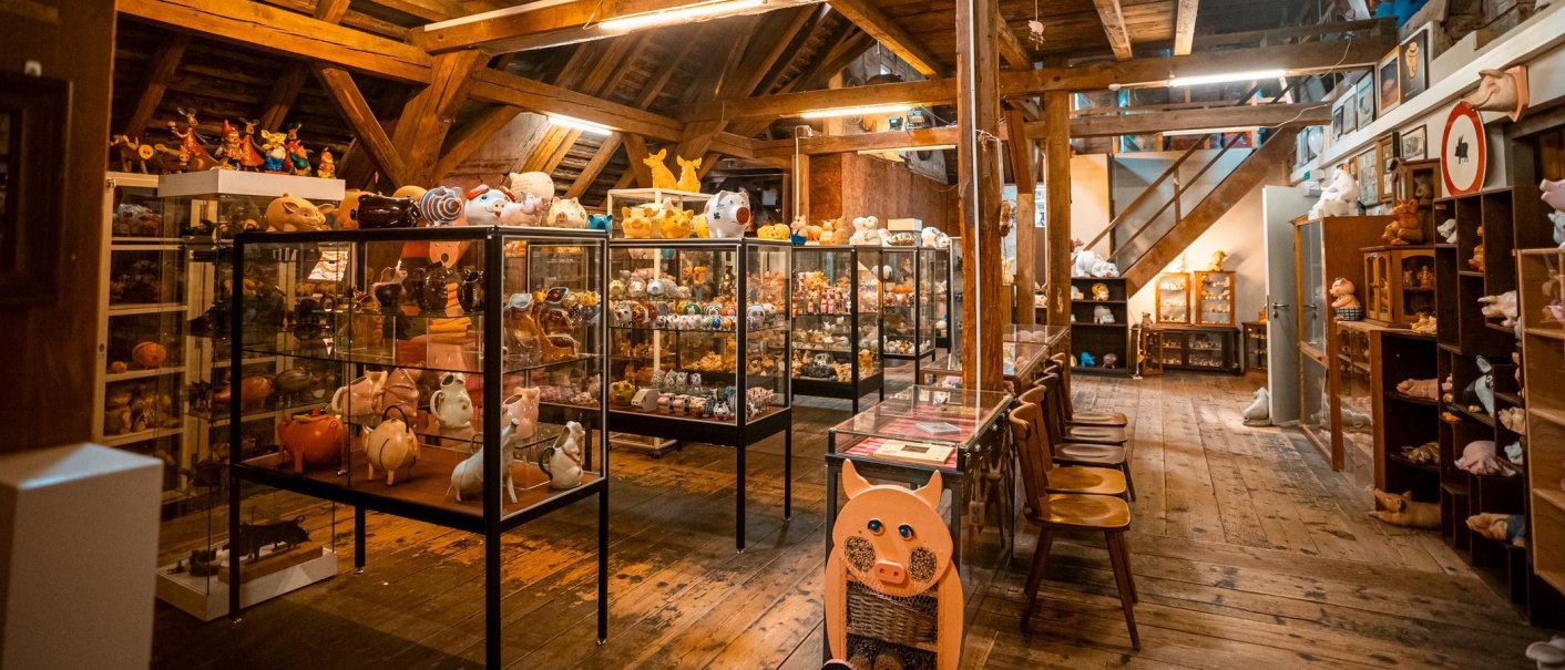 Ein Raum im Schweinemuseum mit zahlreichen Schweinefiguren in Vitrinen und Regalen, umgeben von Holzbalken und Holzboden., © Stuttgart-Marketing GmbH, Sarah Schmid Ein Raum im Schweinemuseum mit zahlreichen Schweinefiguren in Vitrinen und Regalen, umgeben von Holzbalken und Holzboden., © Stuttgart-Marketing GmbH, Sarah Schmid