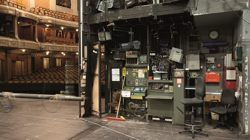 Blick von der Bühne eines Theaters auf den Technikbereich mit Schaltpulten und leeren Zuschauerrängen im Hintergrund., © Württembergische Staatstheater Stuttgart