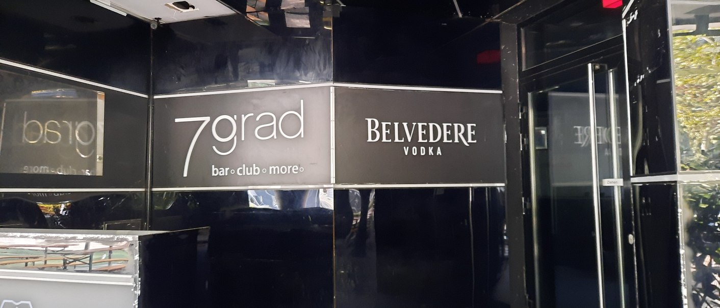 Eingang zur 7grad Bar mit schwarzem Interieur und Belvedere Vodka Werbung. Glastür mit "Ziehen"-Schild sichtbar., © SMG
