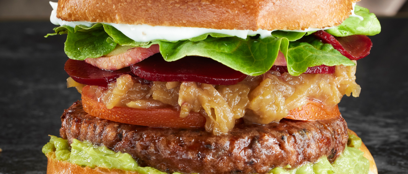 A juicy burger with lettuce, tomato, onions, beet and avocado on a soft bun., © MAREDO A juicy burger with lettuce, tomato, onions, beet and avocado on a soft bun., © MAREDO