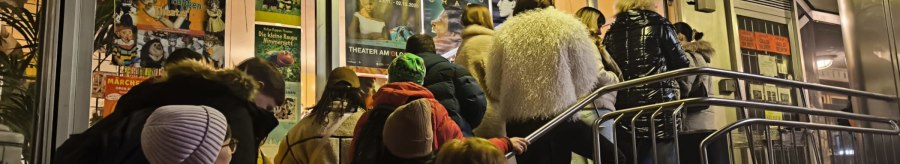 An evening line outside the Theater am Olgaeck in Stuttgart, with posters advertising a puppet show and a film festival., © Theater am Olgaeck An evening line outside the Theater am Olgaeck in Stuttgart, with posters advertising a puppet show and a film festival., © Theater am Olgaeck