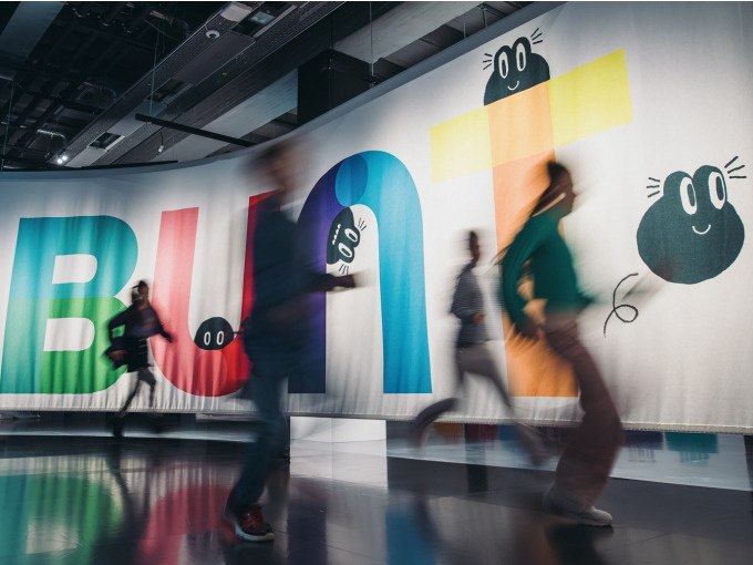 Verschwommene Personen bewegen sich vor einem großen, bunten Banner mit dem Wort 'BUNT' und fröhlichen Gesichtern. Lebendige Atmosphäre., © Landesmuseum Württemberg Verschwommene Personen bewegen sich vor einem großen, bunten Banner mit dem Wort 'BUNT' und fröhlichen Gesichtern. Lebendige Atmosphäre., © Landesmuseum Württemberg