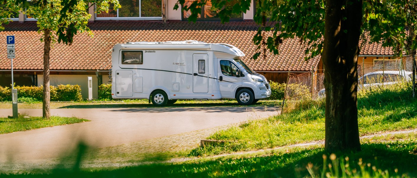 Wohnmobil auf einem Stellplatz neben einem Geb&auml;ude mit Ziegeldach, umgeben von B&auml;umen und Gr&uuml;nfl&auml;chen., &copy; Stuttgart-Marketing GmbH, Thomas Niederm&uuml;ller