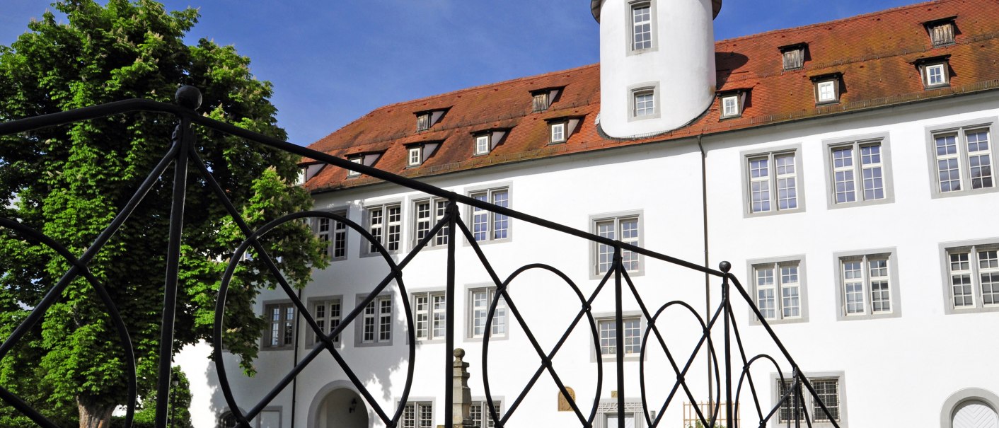 Schloss Waldenbuch mit wei&szlig;er Fassade und rotem Dach, umgeben von B&auml;umen. Ein schmiedeeisernes Gel&auml;nder im Vordergrund., &copy; Gert-Peter Albig, GDA Waldenbuch