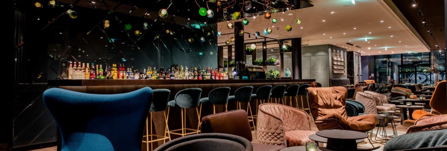 Elegante Bar mit stilvollen Sesseln und Hockern, dekorativen Lampen und einer gut best&uuml;ckten Theke. Gem&uuml;tliche Atmosph&auml;re mit modernem Design., &copy; Motel One - Stuttgart Hauptbahnhof