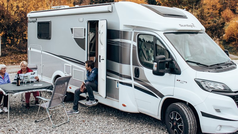 Ein Wohnmobil steht auf einem Stellplatz. Drei Personen sitzen davor an einem Tisch, ein Hund ist ebenfalls zu sehen. Herbstliche Bäume im Hintergrund., © Erlebnisregion Schwäbischer Albtrauf e.V.