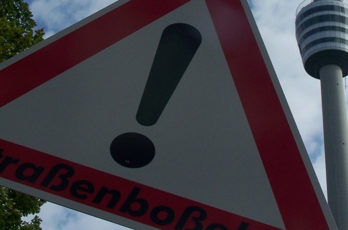 Ein Warnschild für Straßenboßeln mit einem Ausrufezeichen. Im Hintergrund ist ein Fernsehturm zu sehen., © Cool-Tours StattReisen Ein Warnschild für Straßenboßeln mit einem Ausrufezeichen. Im Hintergrund ist ein Fernsehturm zu sehen., © Cool-Tours StattReisen