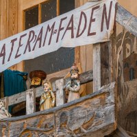 Ein Holzbalkon mit Puppen und einem handgemalten Banner 'Theater am Faden'. Die Puppen sind traditionell gekleidet., &copy; SMG, Sarah Schmid