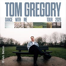 A man is sitting on a bench in a park. The sky is gray. At the top of the picture it says: Tom Gregory - Dance With Me Tour 2026., &copy; see on the left