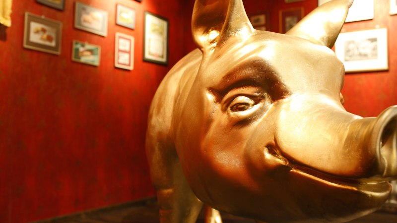 Eine goldene Schweinestatue in einem Museum. Die W&auml;nde sind rot und mit verschiedenen Bildern dekoriert., &copy; SMG,Christoph D&uuml;pper