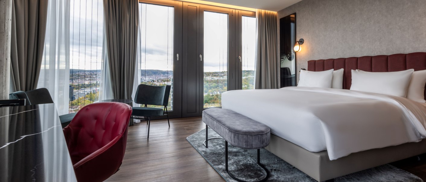 Modern hotel room with a large bed, panoramic windows, stylish furnishings and a view of the city., &copy; Radisson Hotel Group