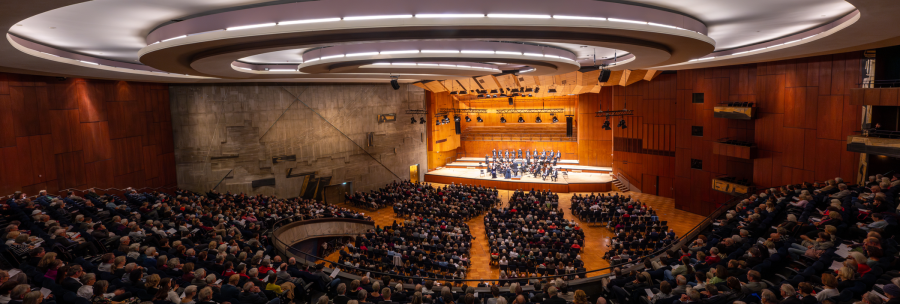 A large concert hall with a modern design, filled with spectators. An orchestra plays on the stage. The architecture is impressive., &copy; Holger Schneider