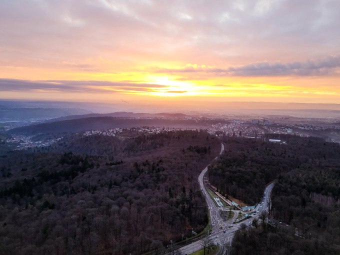 Sunrise over a wooded landscape with roads and a town in the background. The sky is partly cloudy, the sun is shining on the horizon., © SWR Media Services GmbH / Fernsehturm Stuttgart Sunrise over a wooded landscape with roads and a town in the background. The sky is partly cloudy, the sun is shining on the horizon., © SWR Media Services GmbH / Fernsehturm Stuttgart