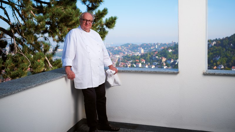 A cook in a white uniform leans against a balcony parapet. A cityscape can be seen in the background., © SMG, Jean-Claude Winkler A cook in a white uniform leans against a balcony parapet. A cityscape can be seen in the background., © SMG, Jean-Claude Winkler