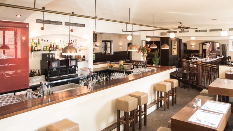 Stilvolles Restaurant mit Bar, Holzmöbeln und gedeckten Tischen. Helle Beleuchtung und gemütliche Atmosphäre., © Amadeus, Stuttgart