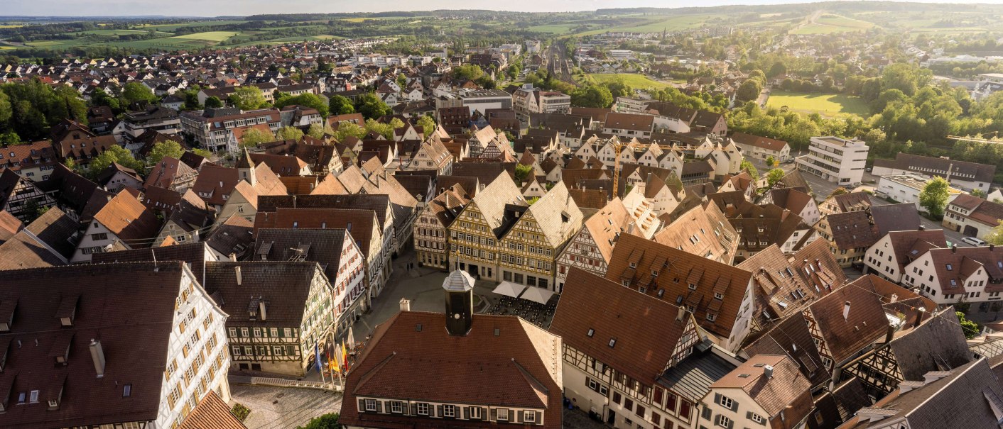 Panorama of a town with many half-timbered houses, surrounded by green countryside and fields under a cloudy sky., © Stuttgart-Marketing GmbH, Martina Denker