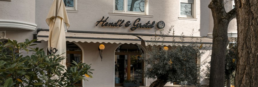 The picture shows the façade of the Hendl & Gretel restaurant with a parasol and plants in the foreground., © SMG Stuttgart Marketing GmbH - Sarah Schmid The picture shows the façade of the Hendl & Gretel restaurant with a parasol and plants in the foreground., © SMG Stuttgart Marketing GmbH - Sarah Schmid