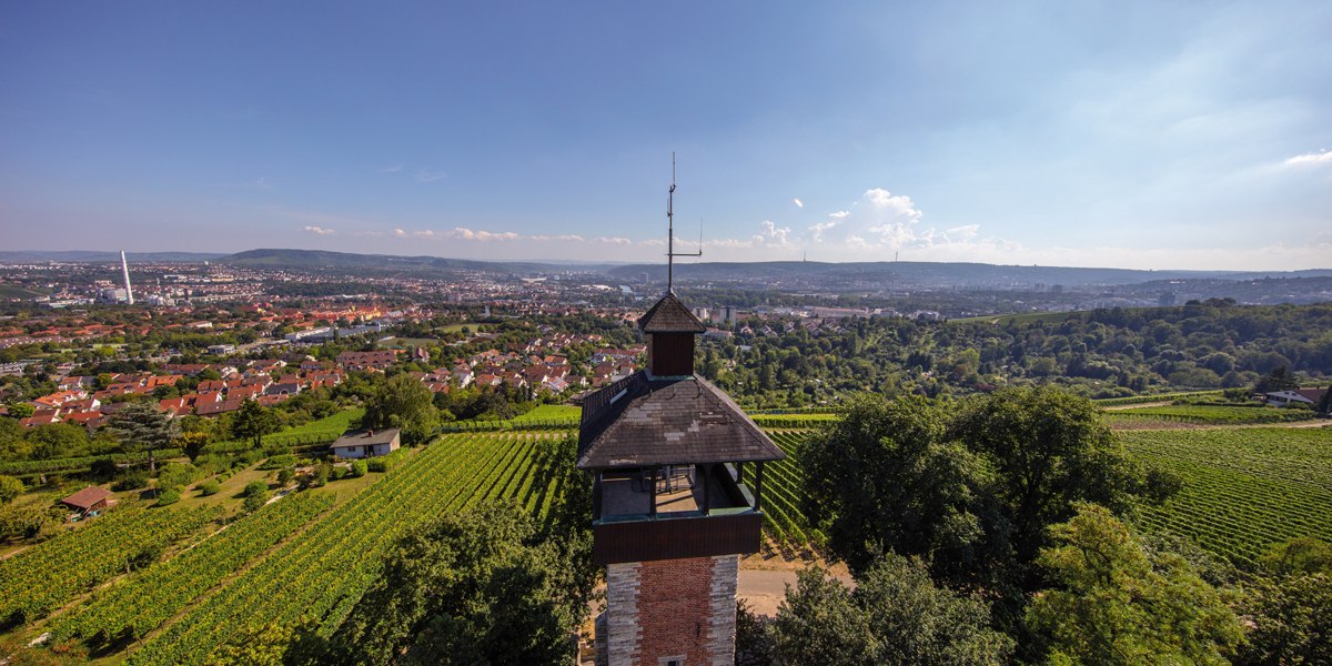 Aussichtsturm Burgholzhof in Stuttgart, umgeben von Weinbergen, mit Blick auf die Stadt und Hügel im Hintergrund unter klarem Himmel., © Stuttgart-Marketing GmbH Aussichtsturm Burgholzhof in Stuttgart, umgeben von Weinbergen, mit Blick auf die Stadt und Hügel im Hintergrund unter klarem Himmel., © Stuttgart-Marketing GmbH